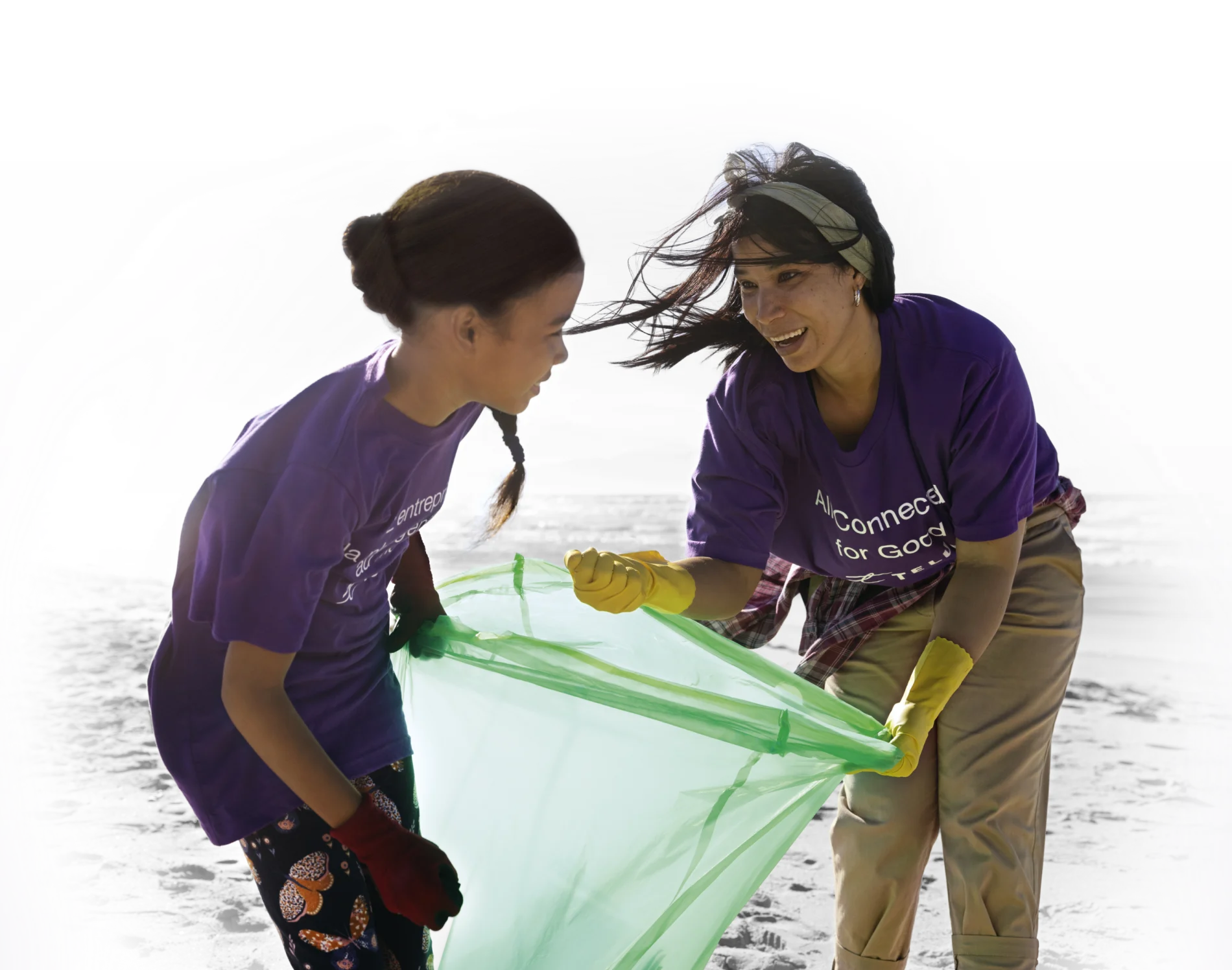 Two volunteers collecting refuse on a beach