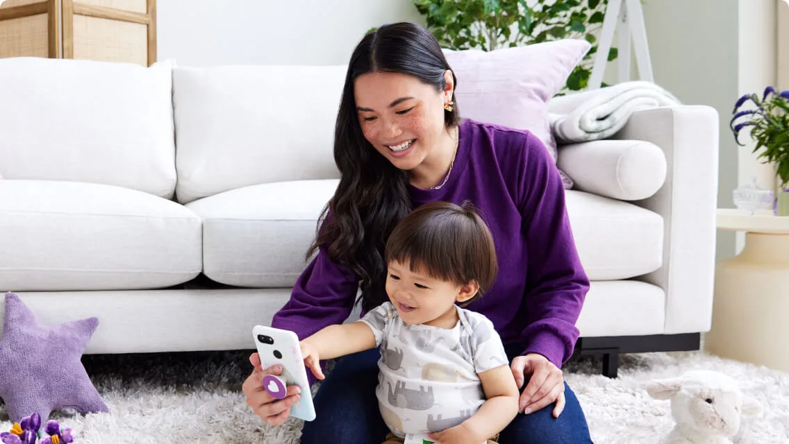 Young mom with her toddler, smiling at phone screen
