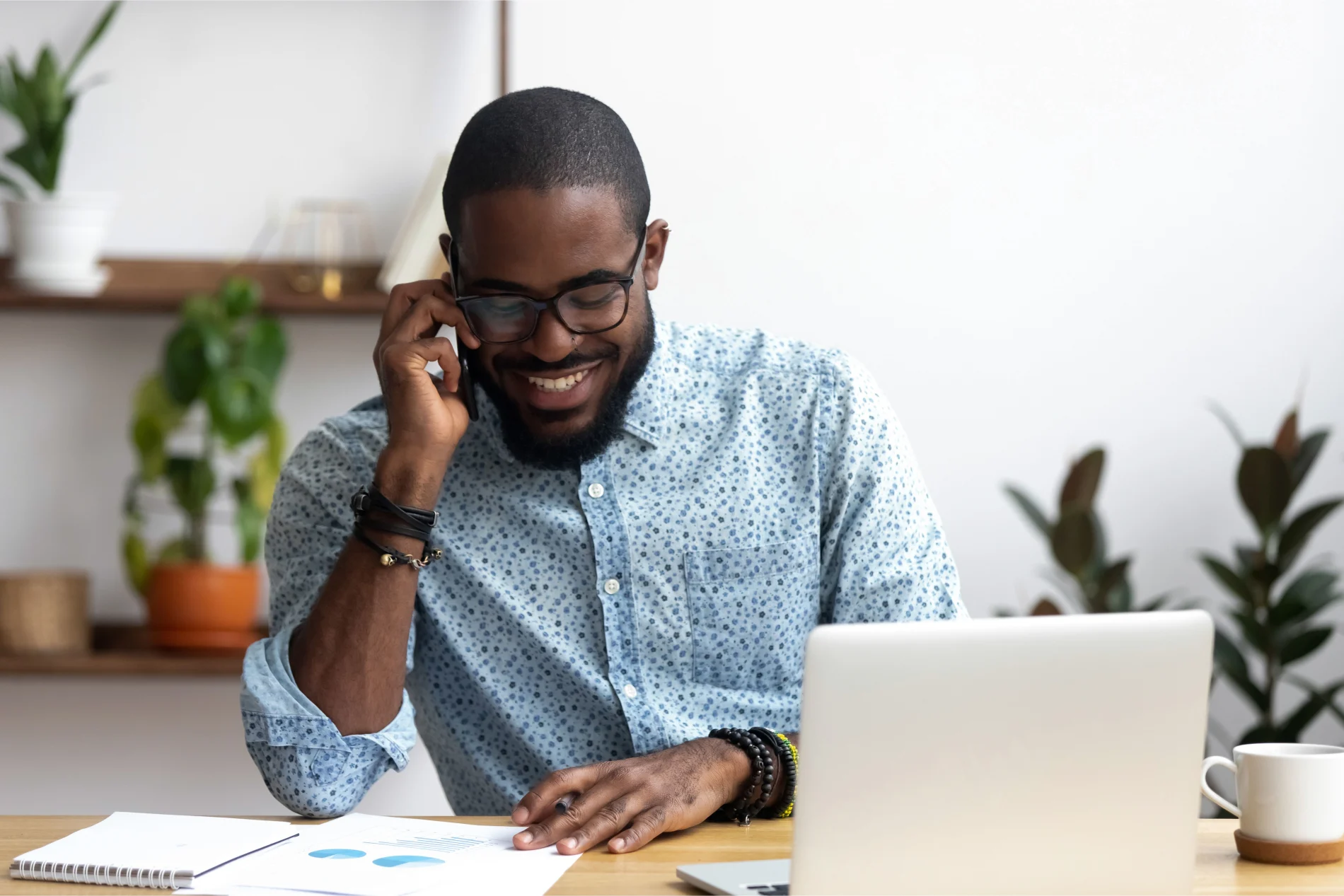 Un homme à son bureau parle sur son téléphone intelligent