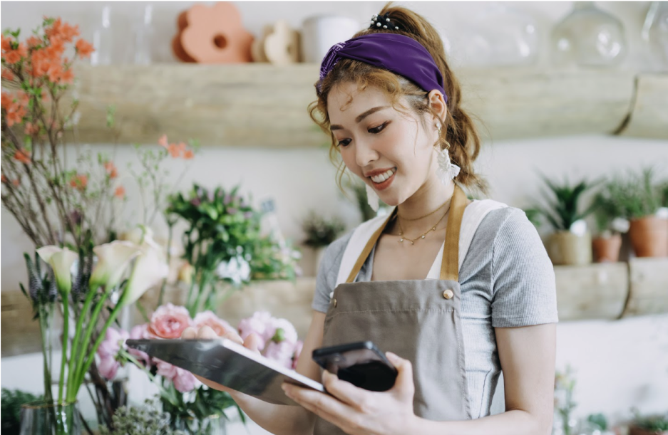 Femme avec une tablette en main dans une boutique de fleurs