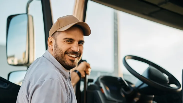 Male truck driver smiling as he steps into the cab of a semi-truck