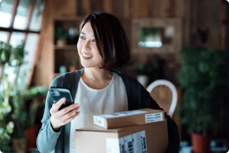 Pendant qu’uelle envoyant un SMS et en transportant des appareils, une femme regarde par la fenêtre.