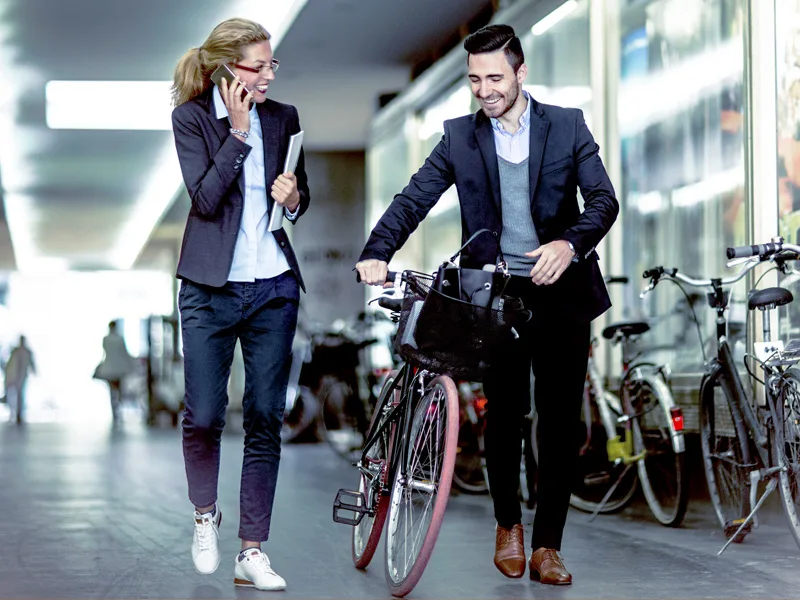 Two people in business wear walking a bike