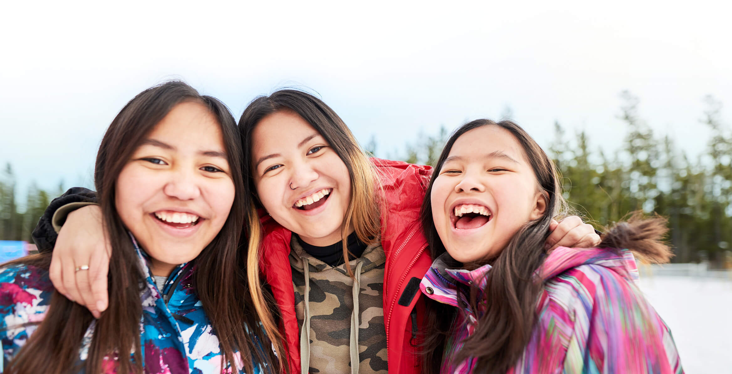 Three teenage girls laughing and smiling as they look forward to the future.