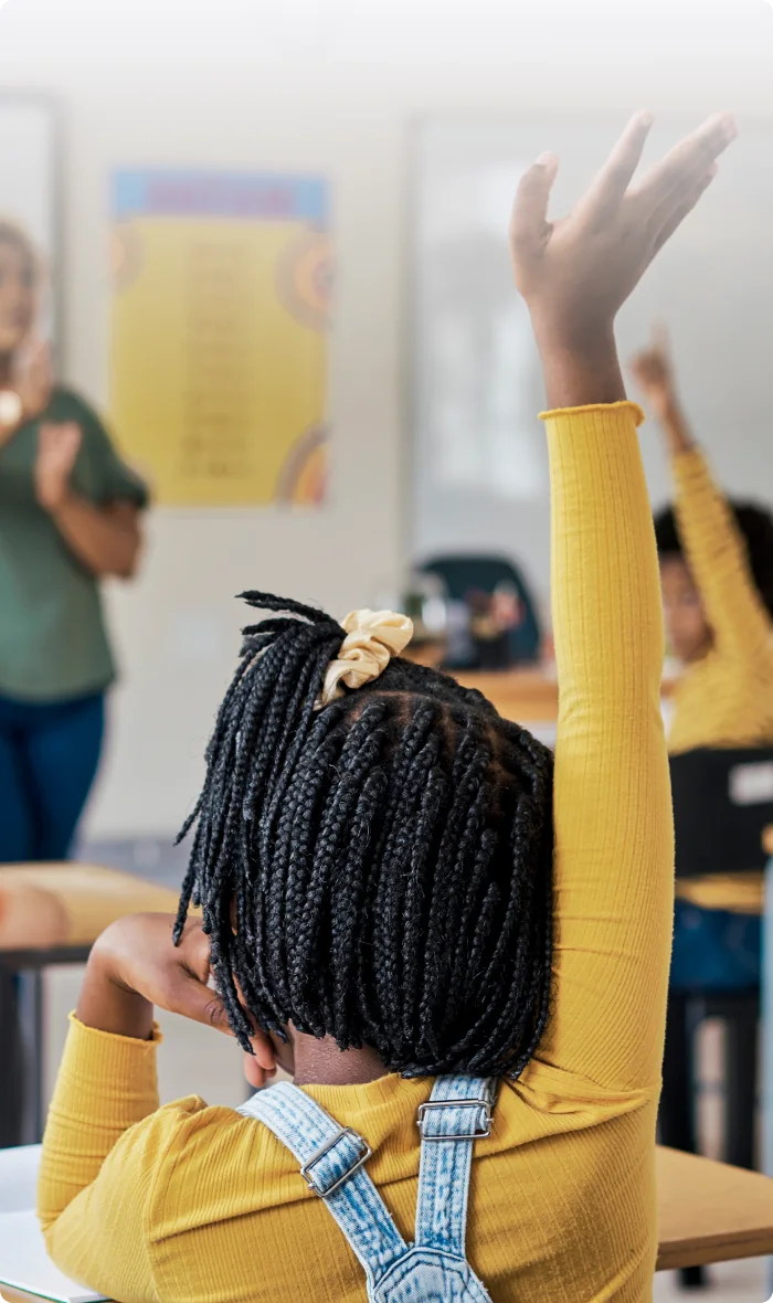 A TELUS Wise educator facing a classroom full of children raising their hands