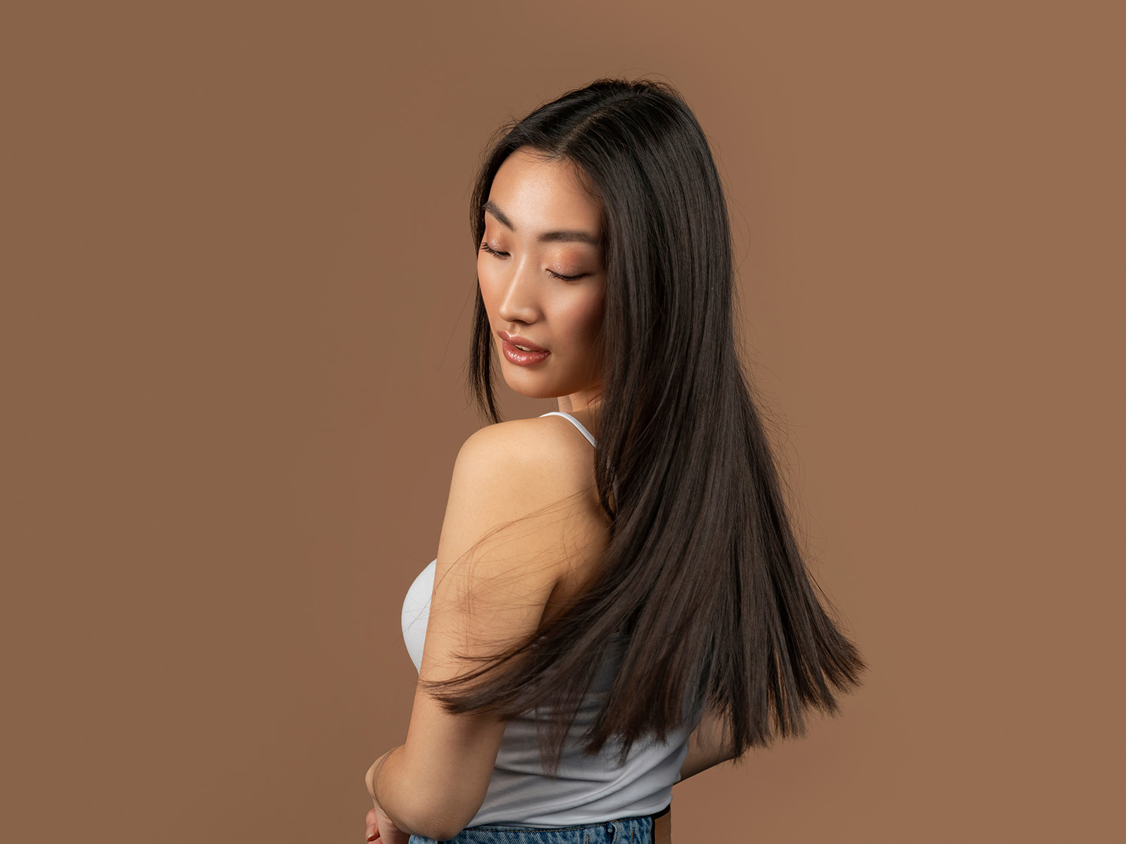 Persona con capelli scuri fluenti, in luce soffusa.