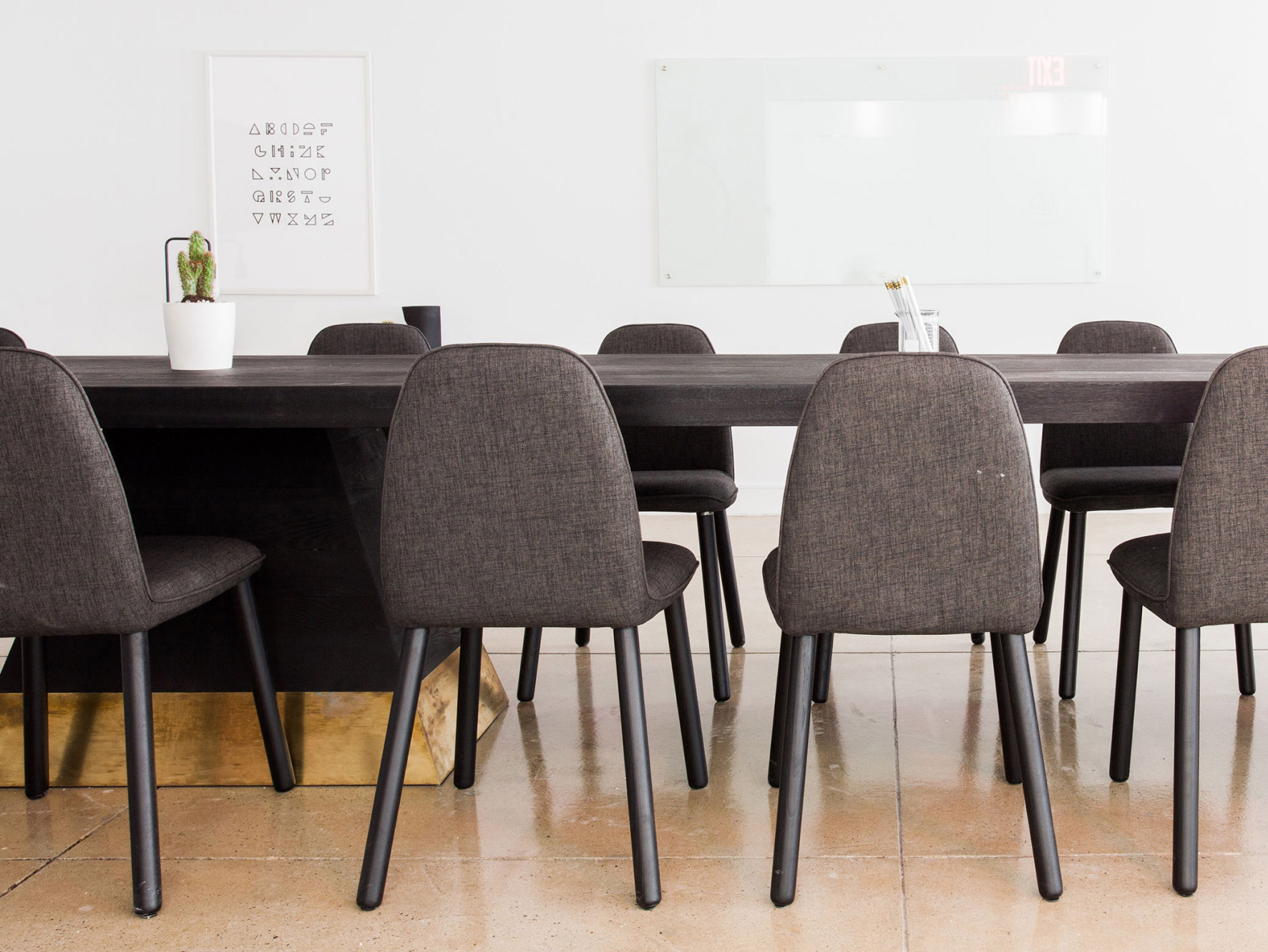 A picture of grey chairs at a black conference table