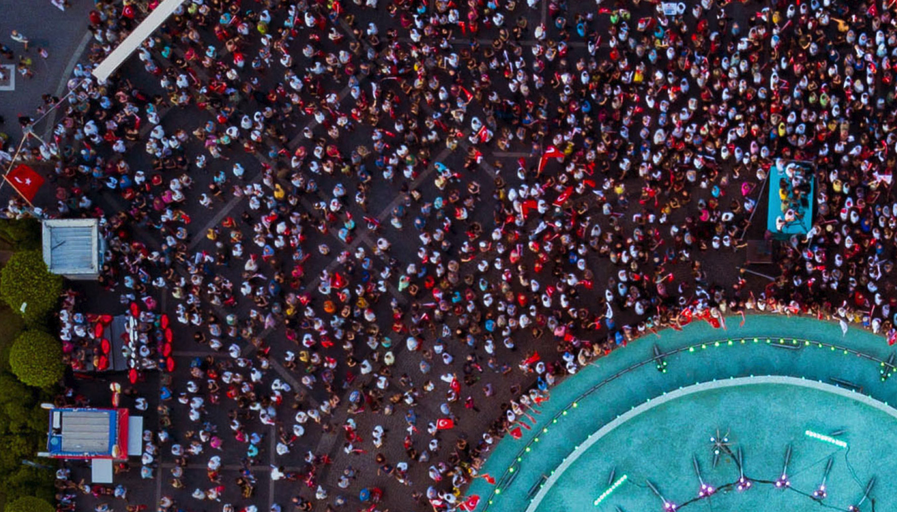 Aerial view of a crowd of people gathering around a blue stage. 