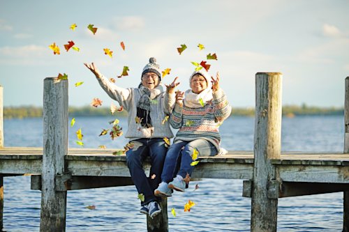 Image of stress free retired couple throwing leaves in the air