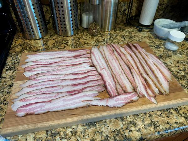 A board covered with slices of homemade smoked bacon.