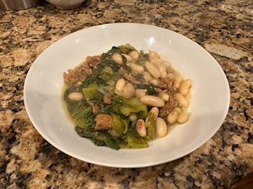 A plate of Italian sausage and white beans with escarole.