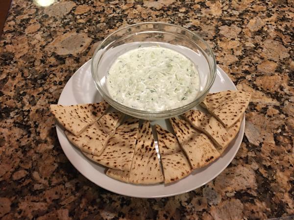 A plate of tzatziki and sliced pita wedges.