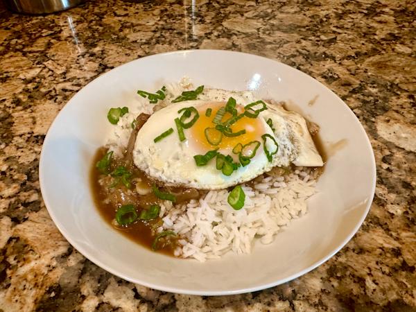 A dish of loco moco topped with chopped green onion.