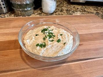 A bowl of white bean puree topped with chopped parsley.