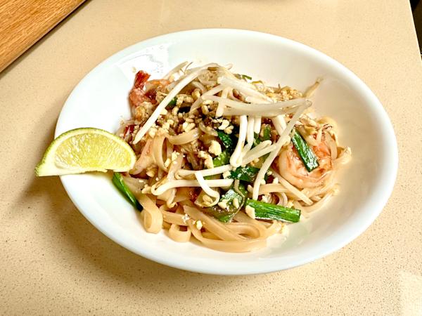 A plate of pad thai with lime.