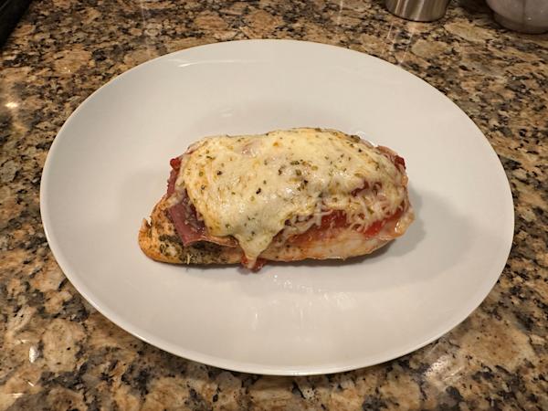A roasted chicken breast with prosciutto and melted mozzarella cheese.