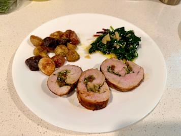 Slices of apricot-stuffed pork with roast potatoes and sautéd greens.