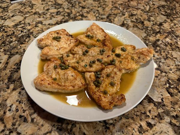 A plate of chicken piccata with capers