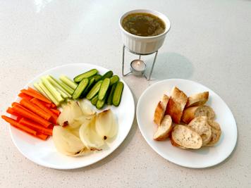A dish of bagna cauda with vegetables and bread for dipping.