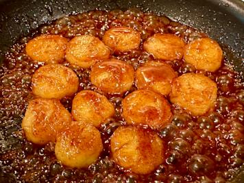 A skillet with fried bananas in a brown sugar glaze.
