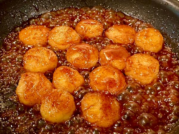 A skillet with fried bananas in a brown sugar glaze.