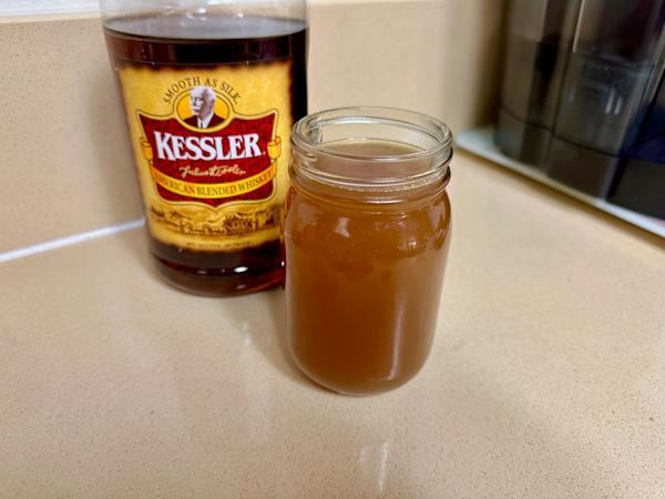 A mason jar of boilo next to a bottle of Kessler whiskey.