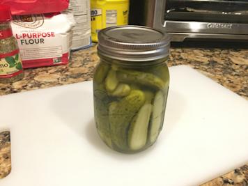 An open mason jar filled with pickle slices.
