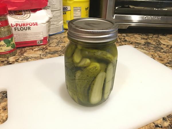An open mason jar filled with pickle slices.