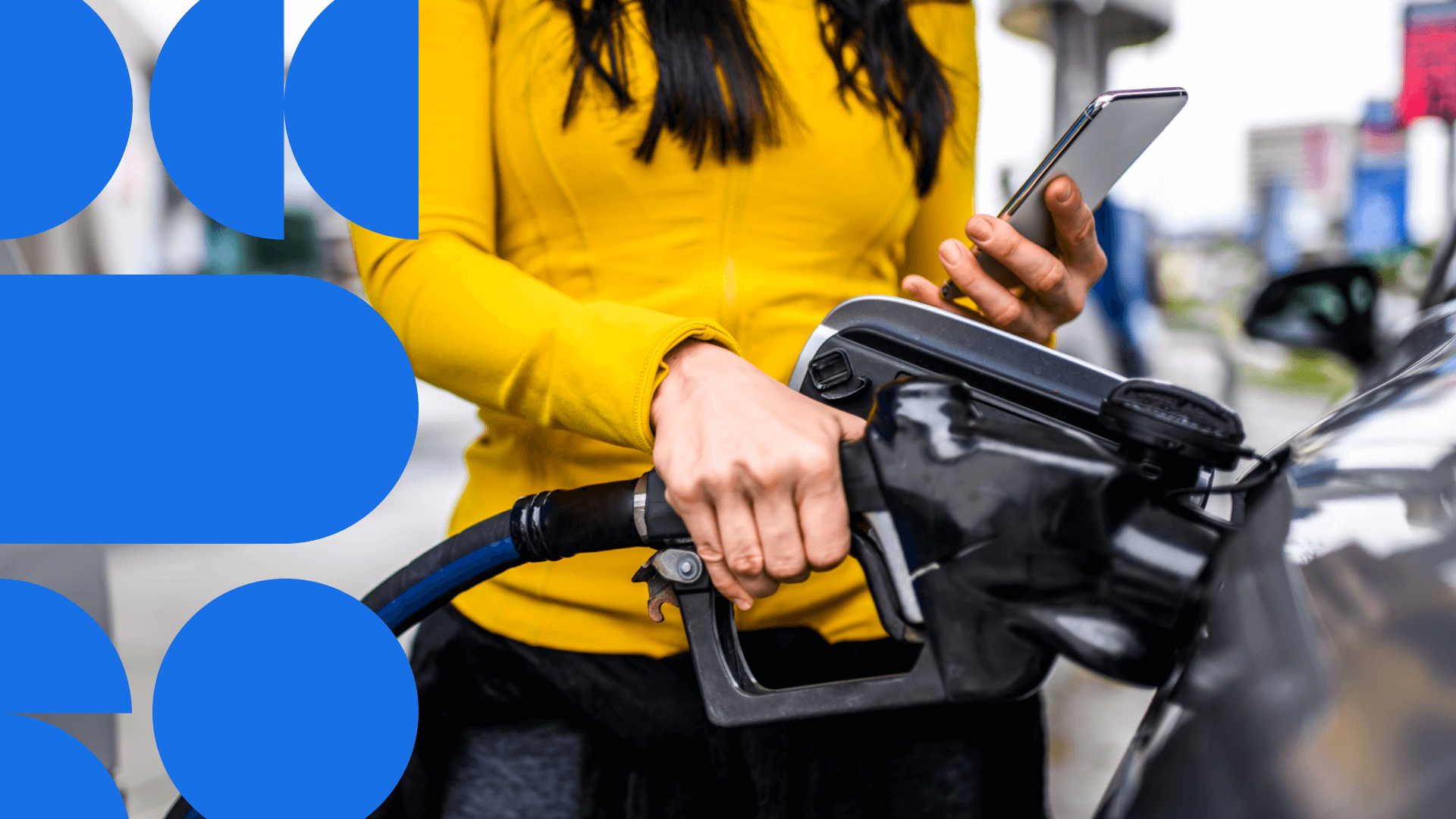Person in yellow jacket using smartphone while holding a pump at a gas station, with blue circular design elements in background