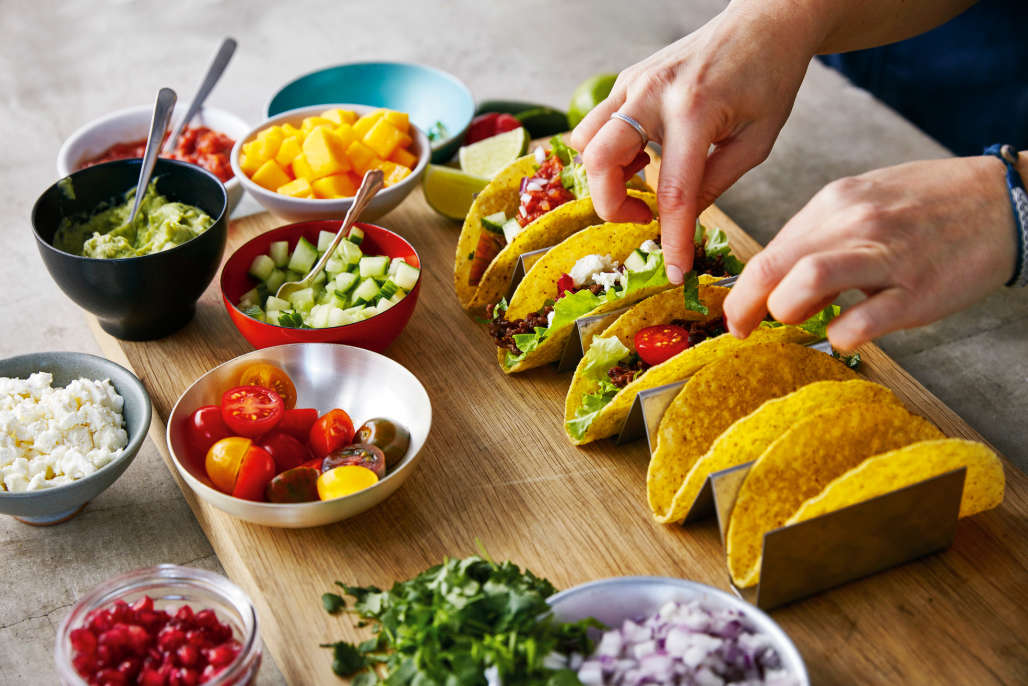 Person preparing tacos with fresh ingredients