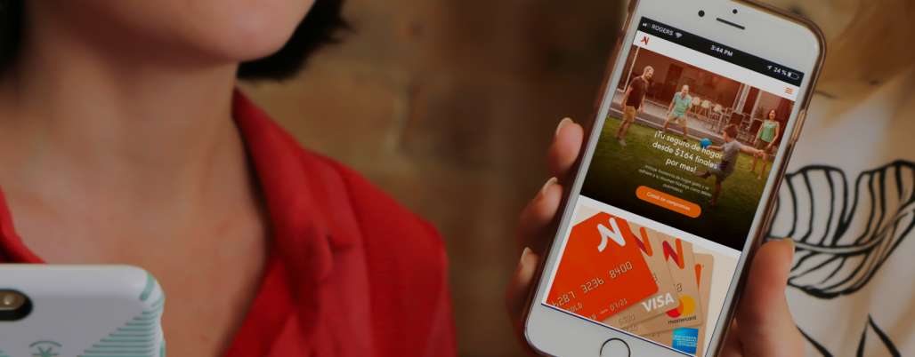 Woman holding a smartphone that shows Naranja X's website