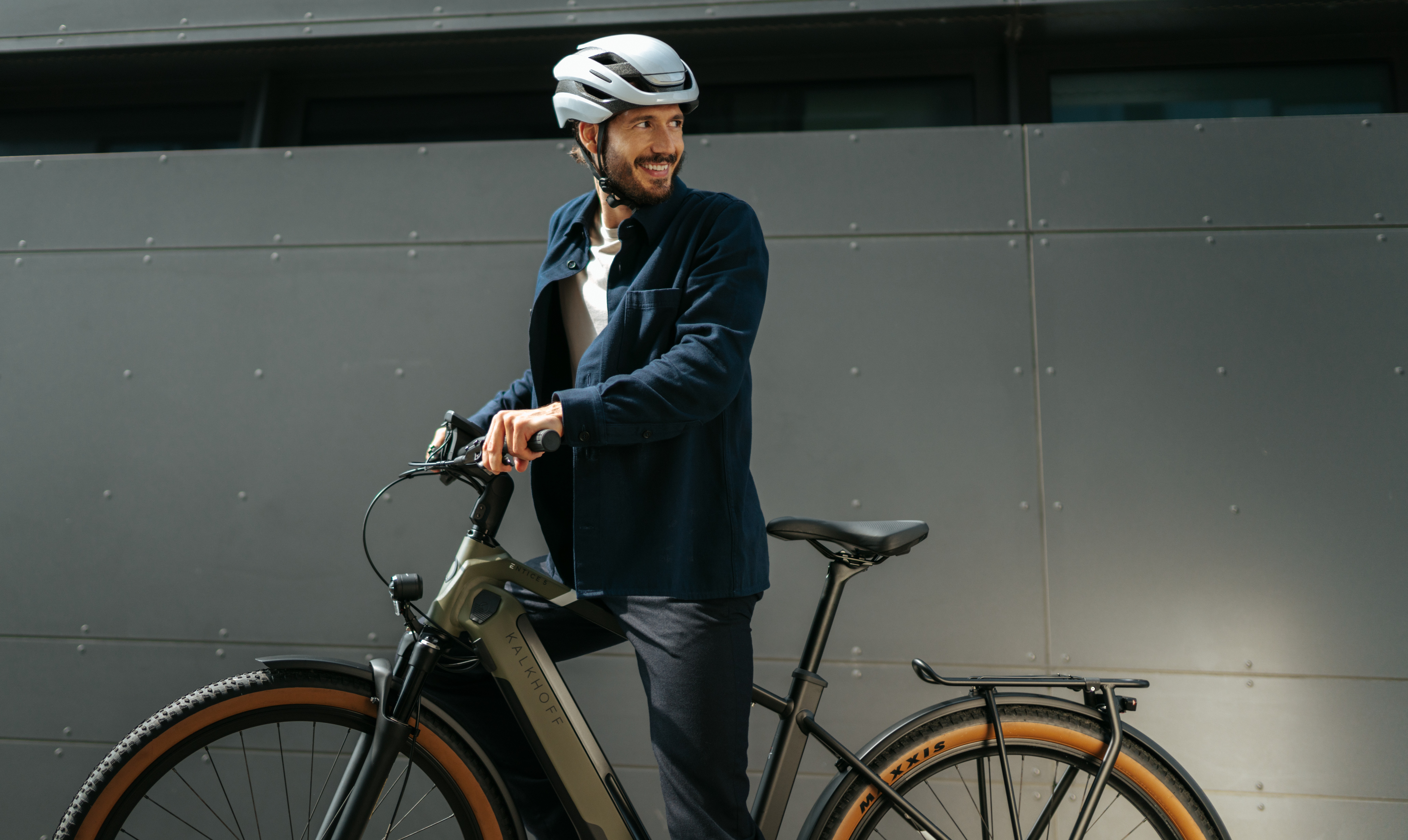 Mann mit E-Bike vor grauer Wand