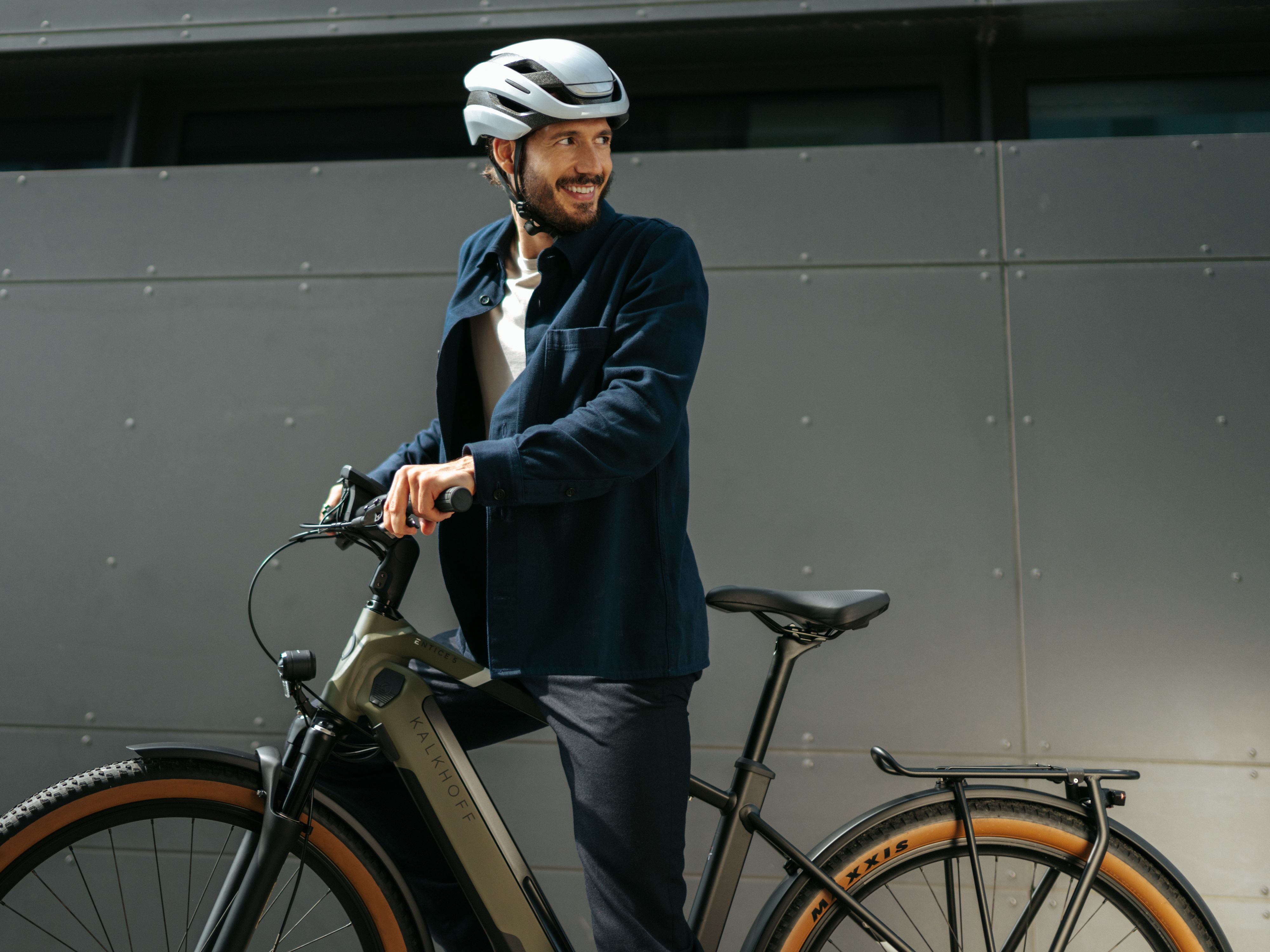 Mann mit E-Bike vor grauer Wand