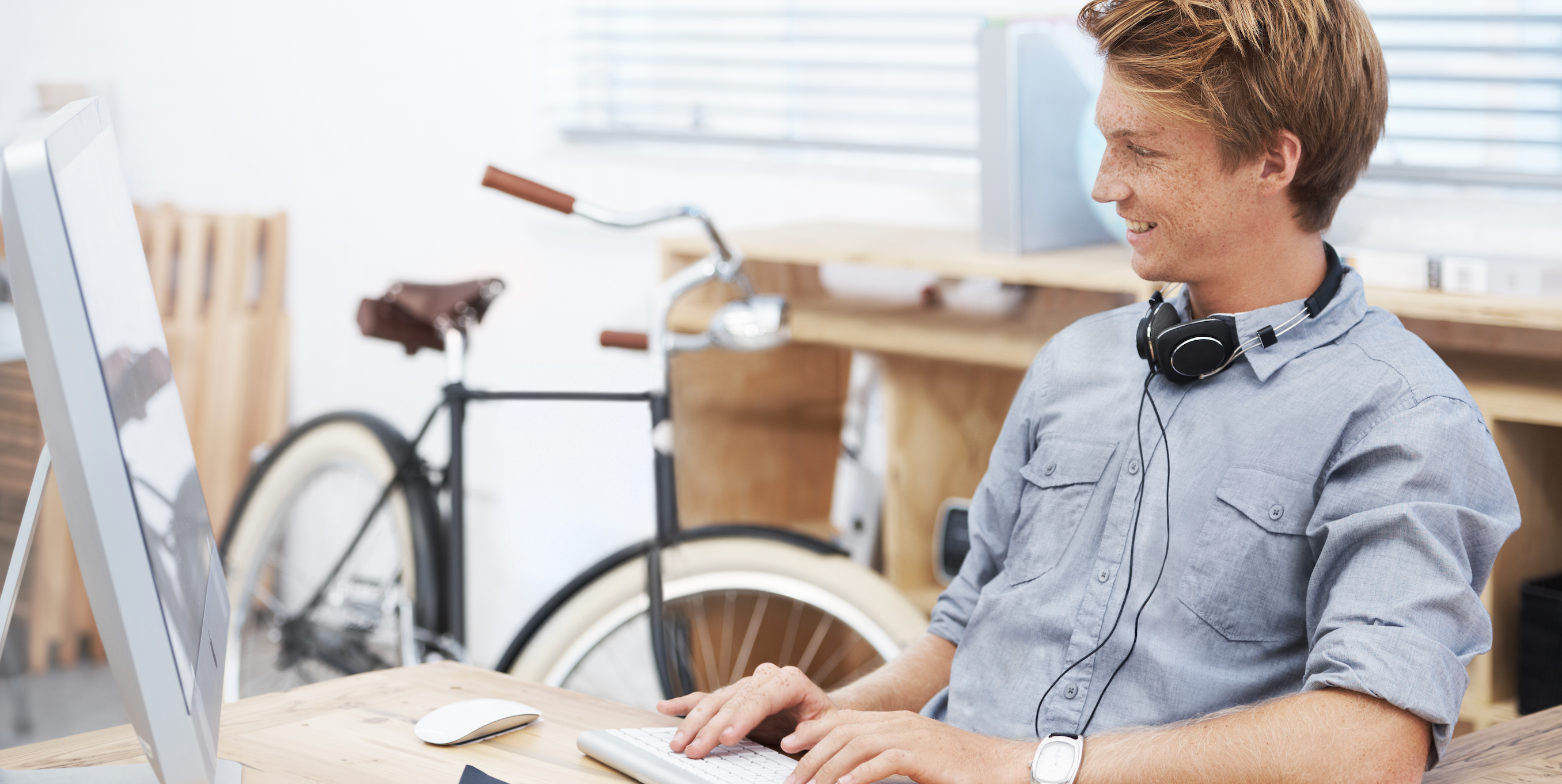 Mann am Schreibtisch mit Fahrrad im Hintergrund