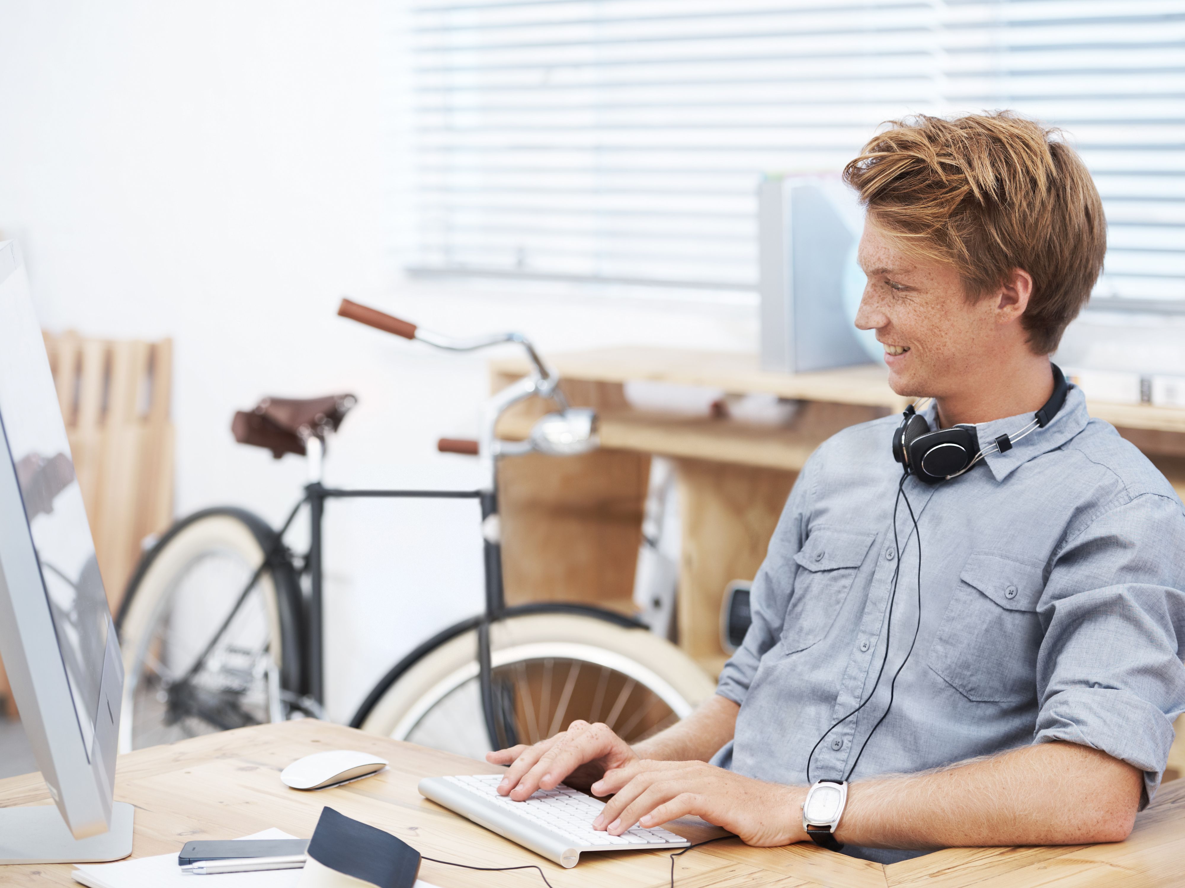 Junger Mann am Schreibtisch mit Fahrrad im Hintergrund