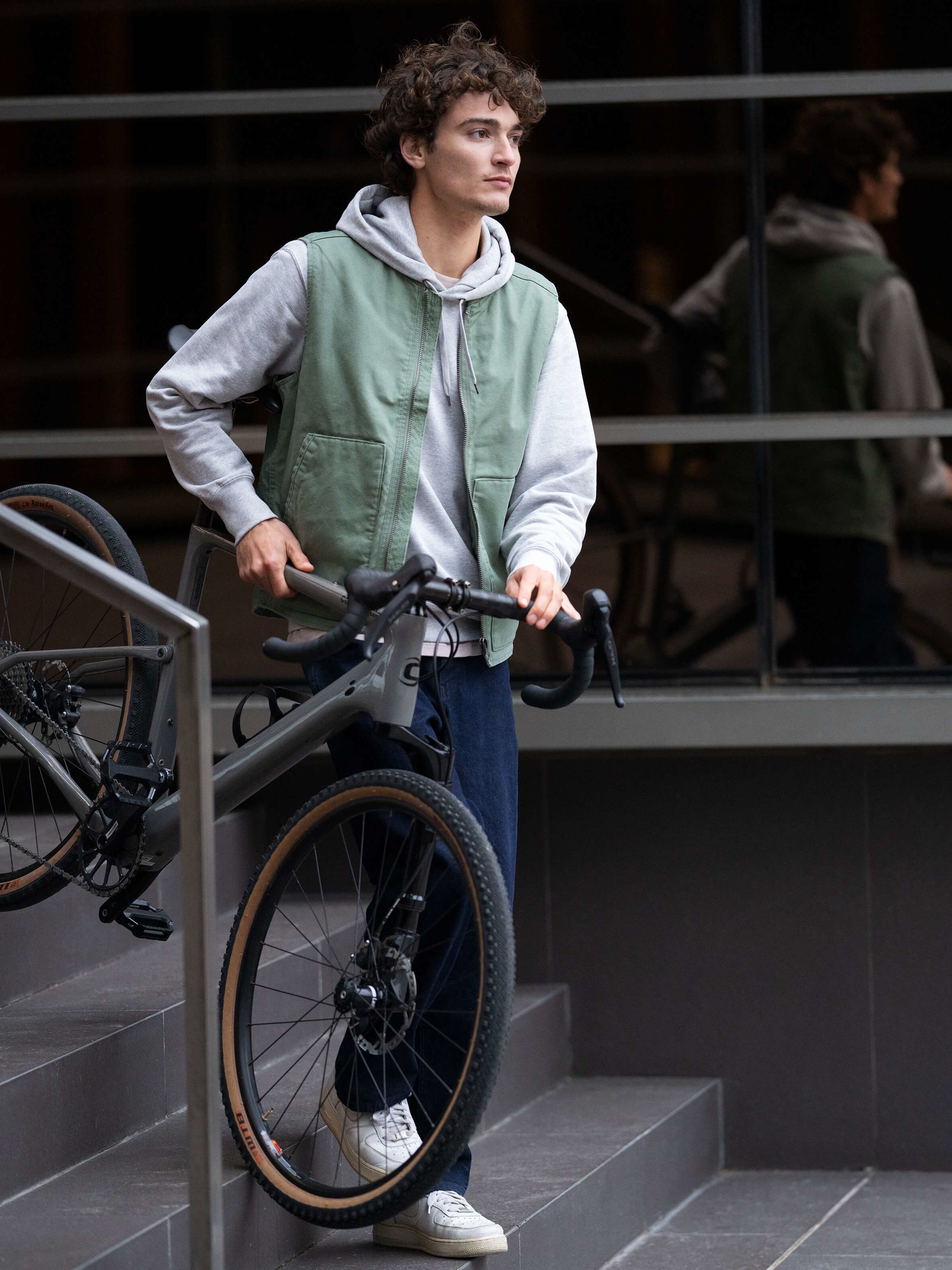 Junge, der sein Fahrrad eine Treppe herunter trägt