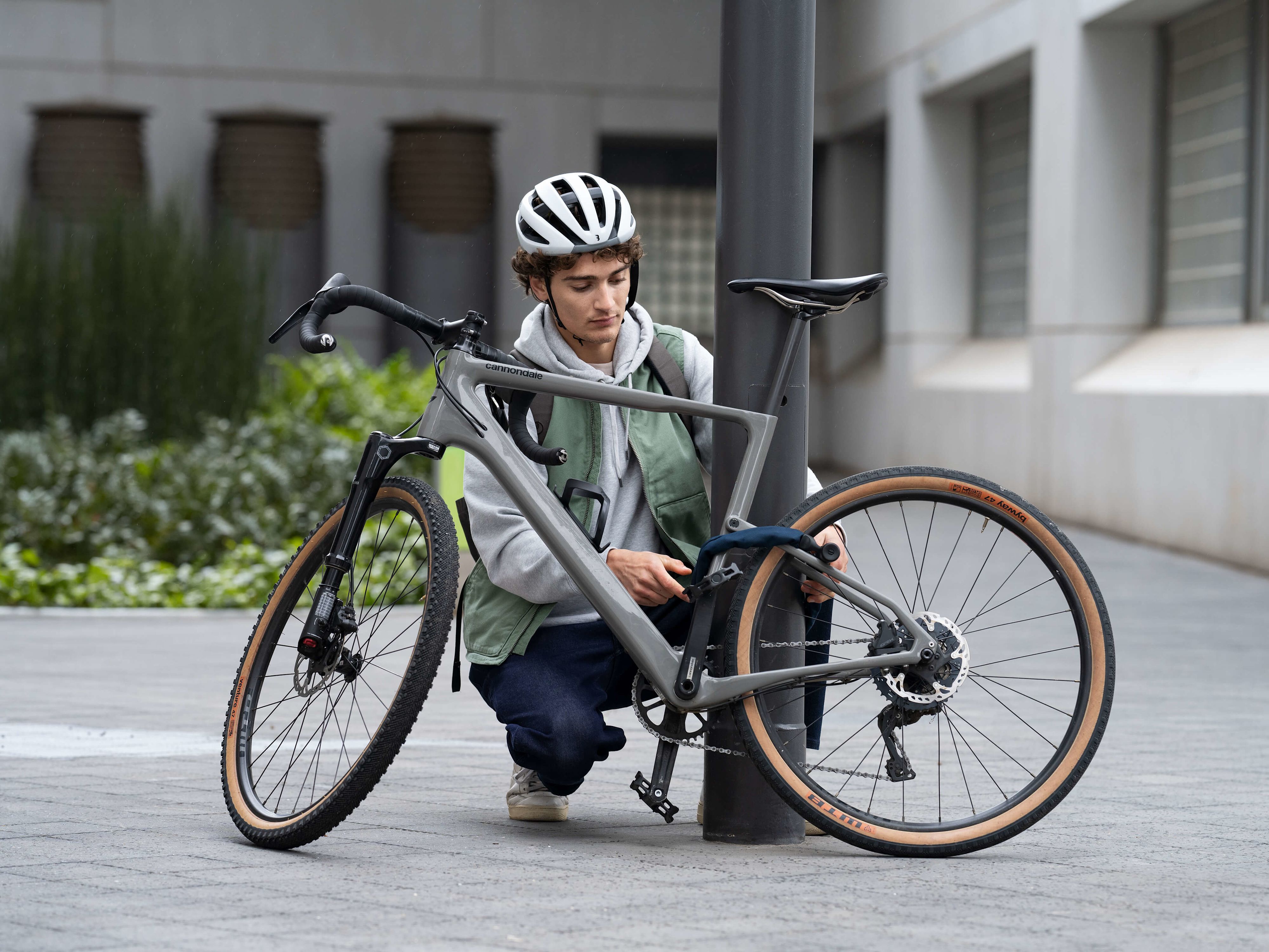 Junger Mann der sein Fahrrad an einer Laterne anschließt
