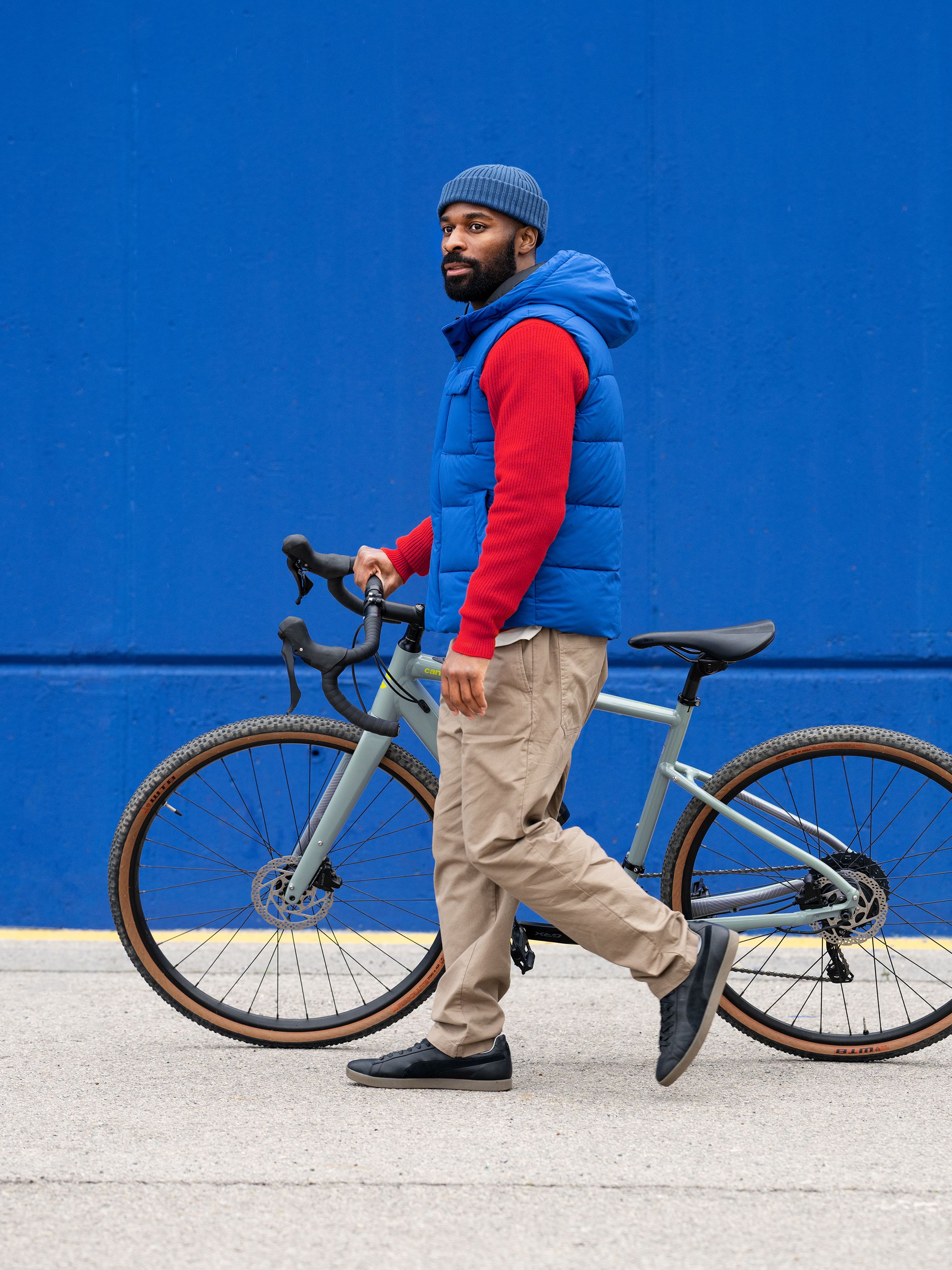 Mann in bunter Übergangskleidung, der sein Fahrrad schiebt