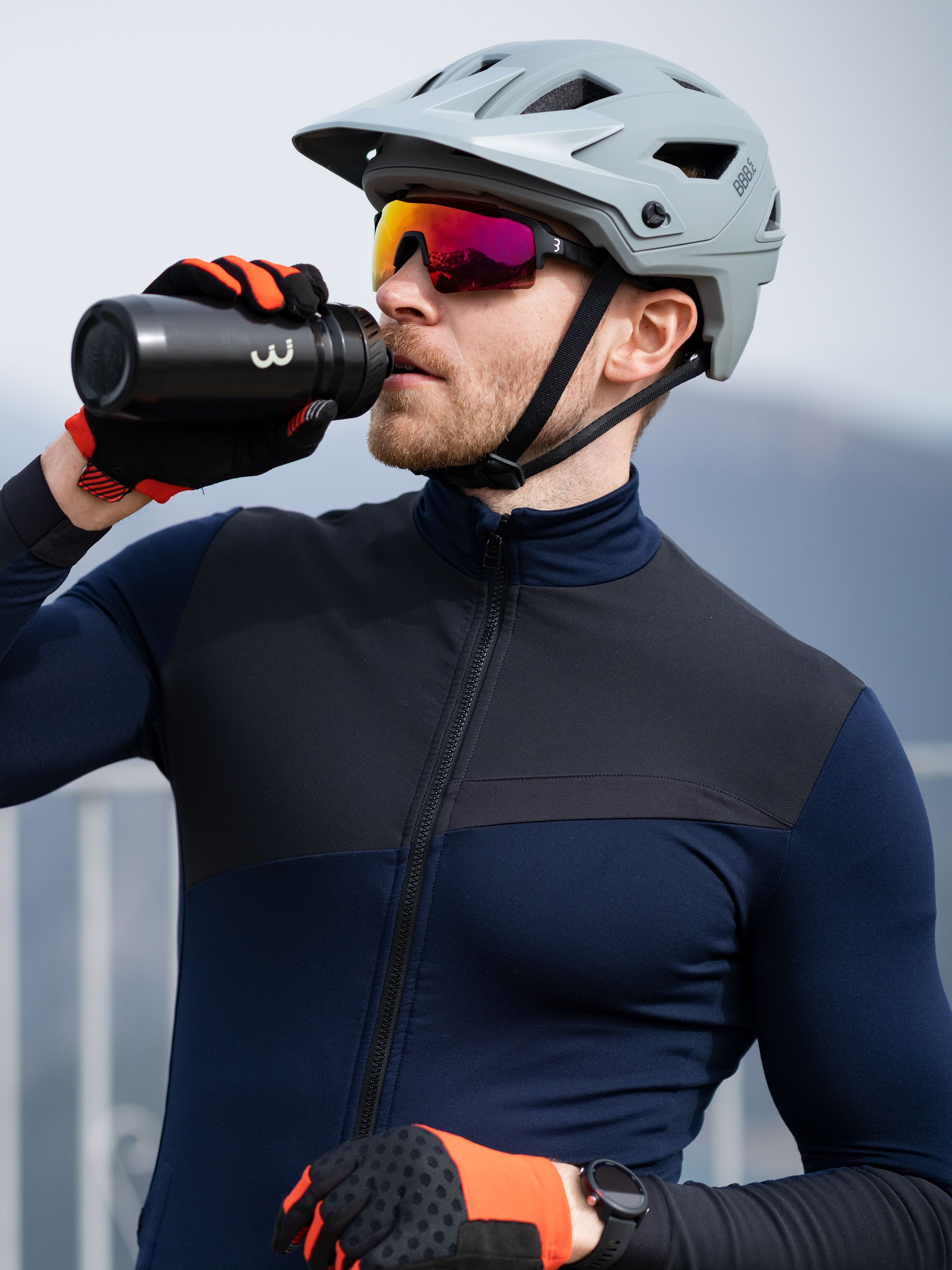 Junger Mann mit Helm aus einer Wasserflasche trinkend