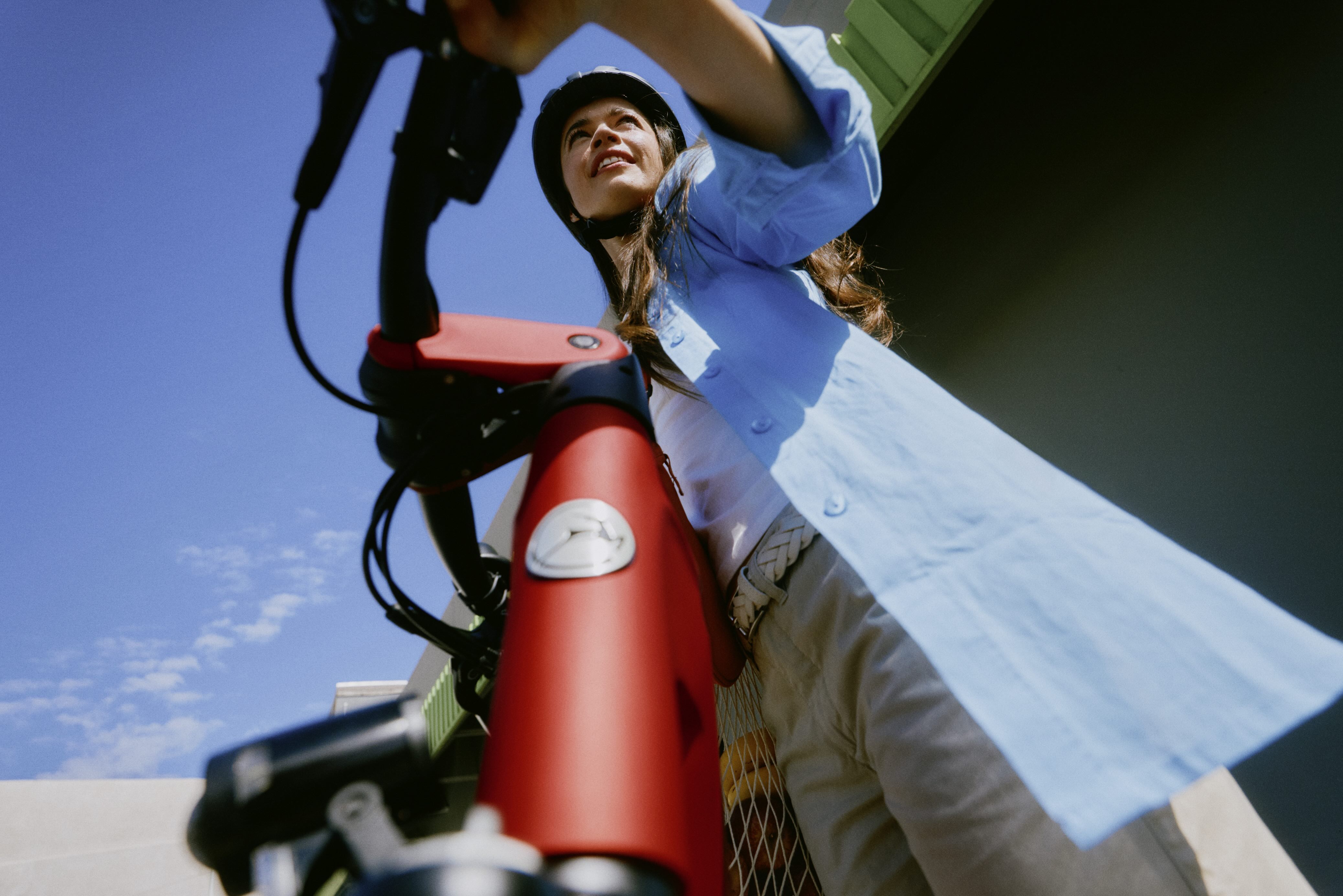 Frau mit offenem Haar, die ihr Fahrrad schiebt