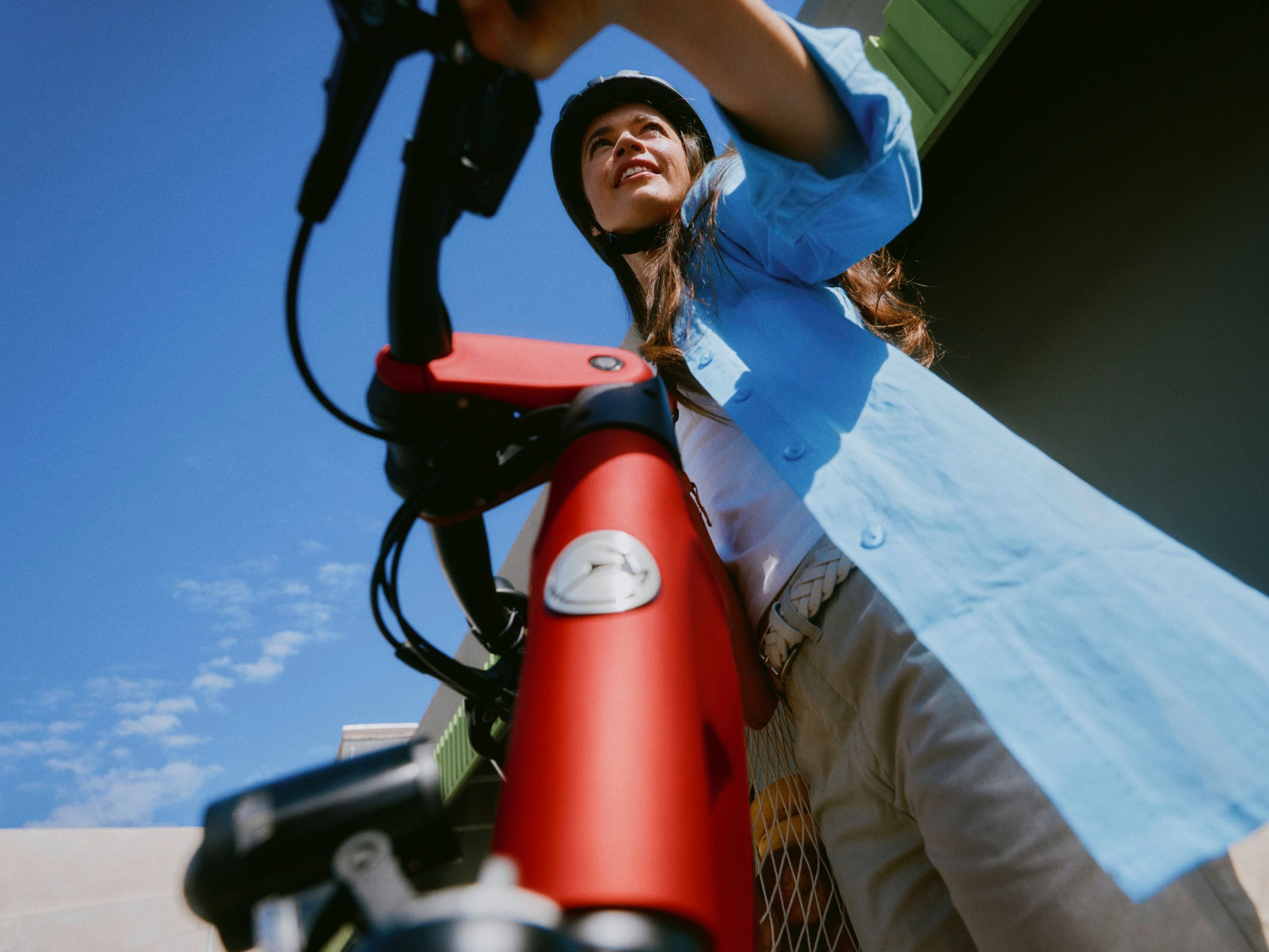 Frau mit offenem Haar, die ihr Fahrrad schiebt