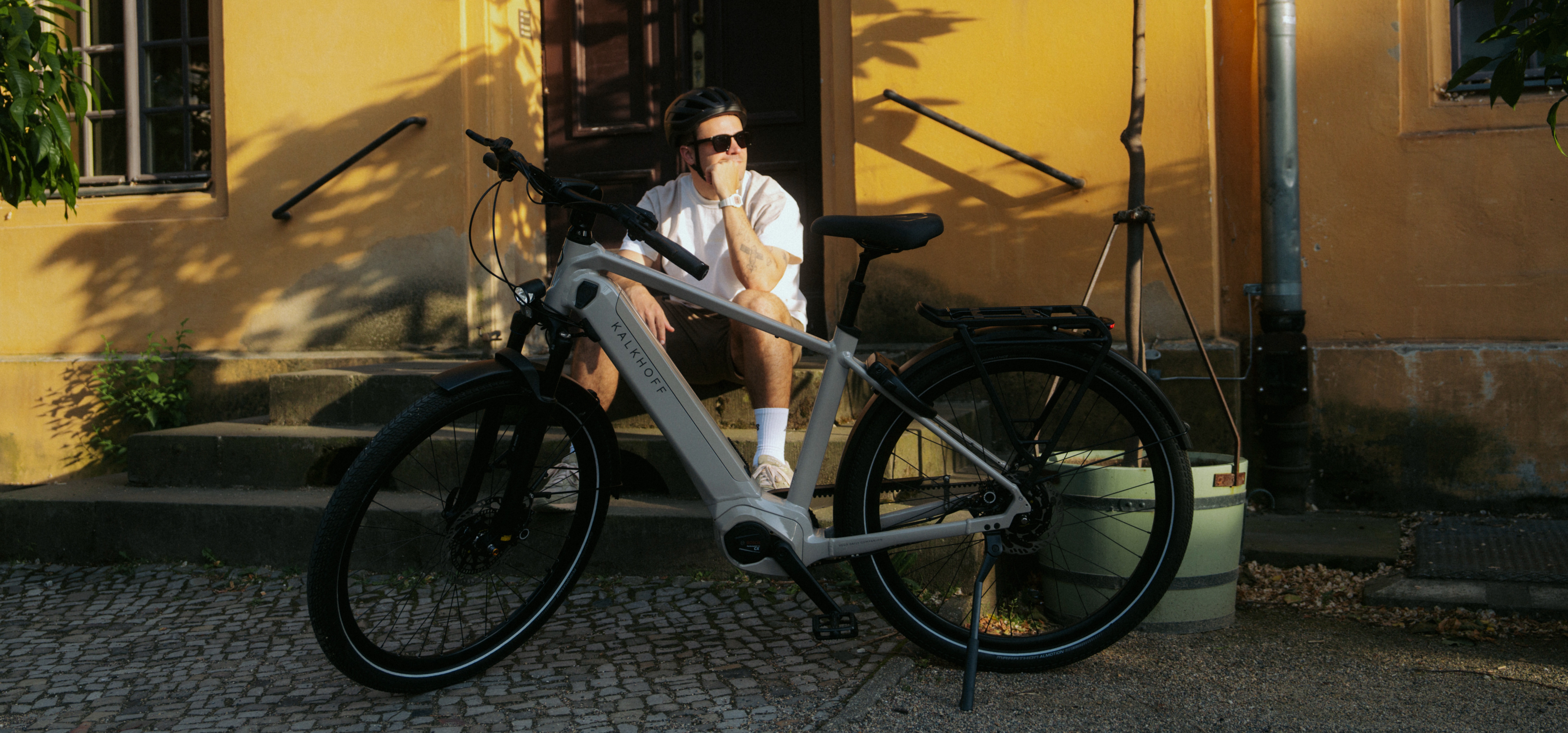 Mann mit E-Bike vor gelber Wand