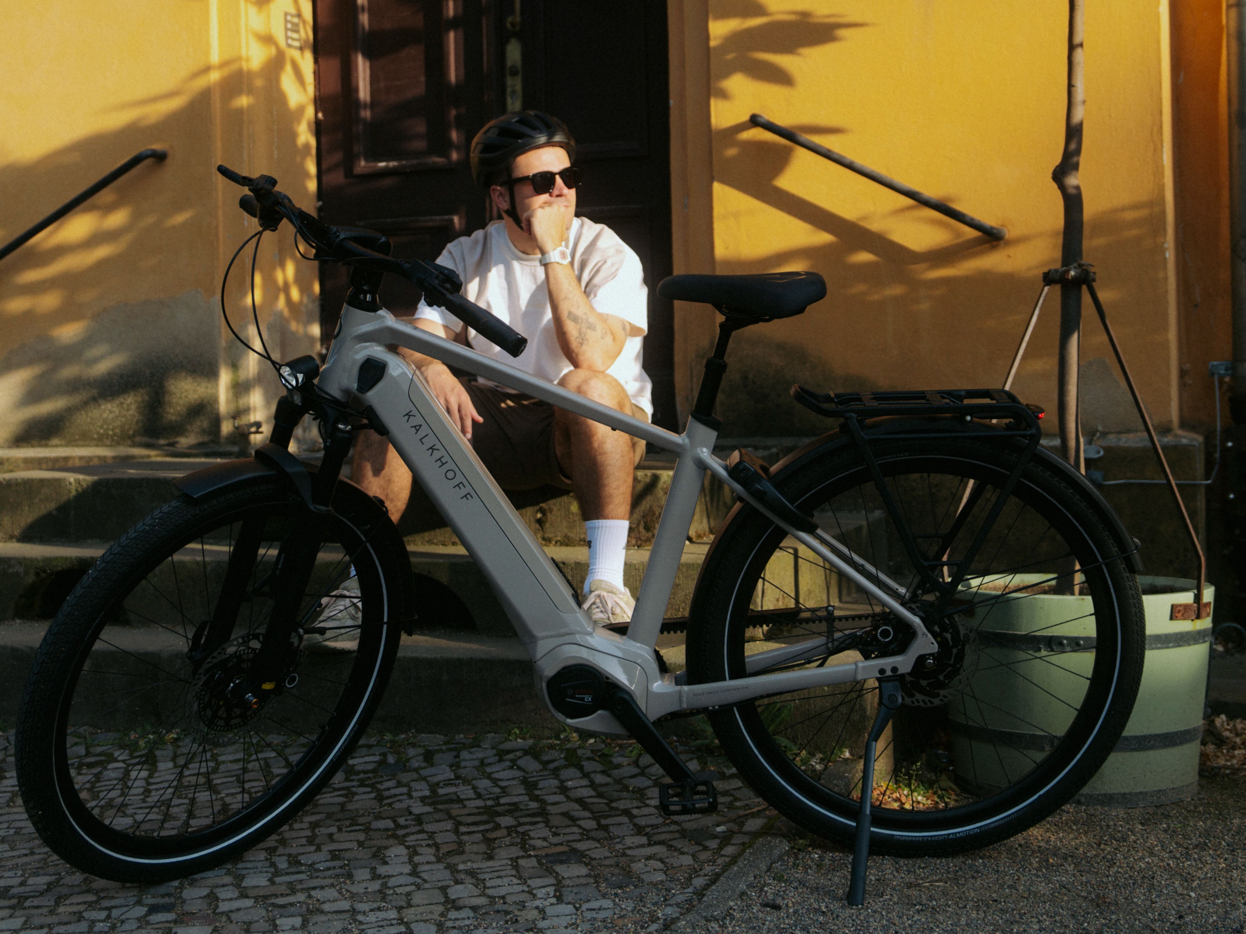Mann mit E-Bike vor gelber Wand