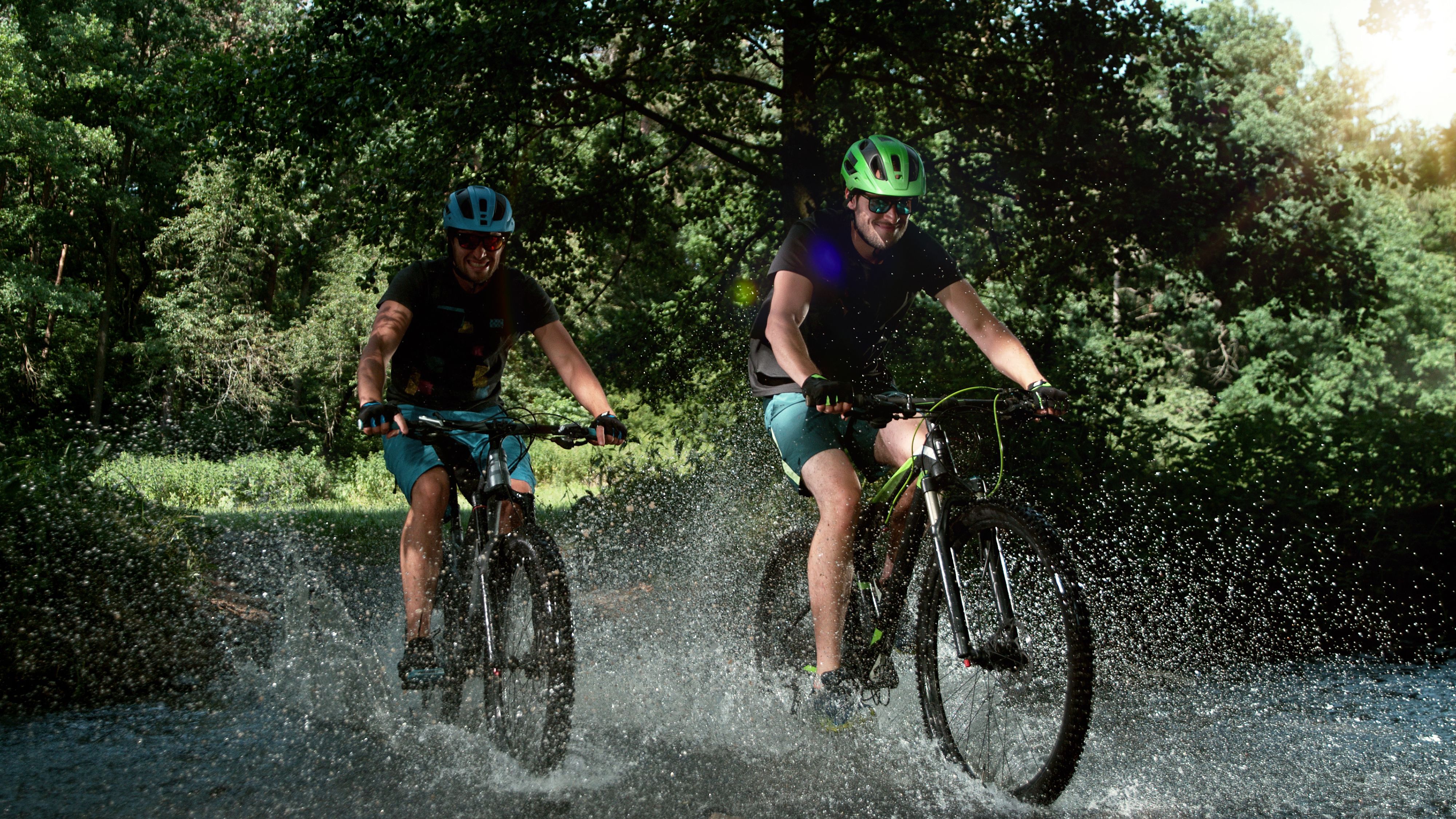 Zwei Fahrradfahrer die mit Mountainbikes durchs Wasser fahren