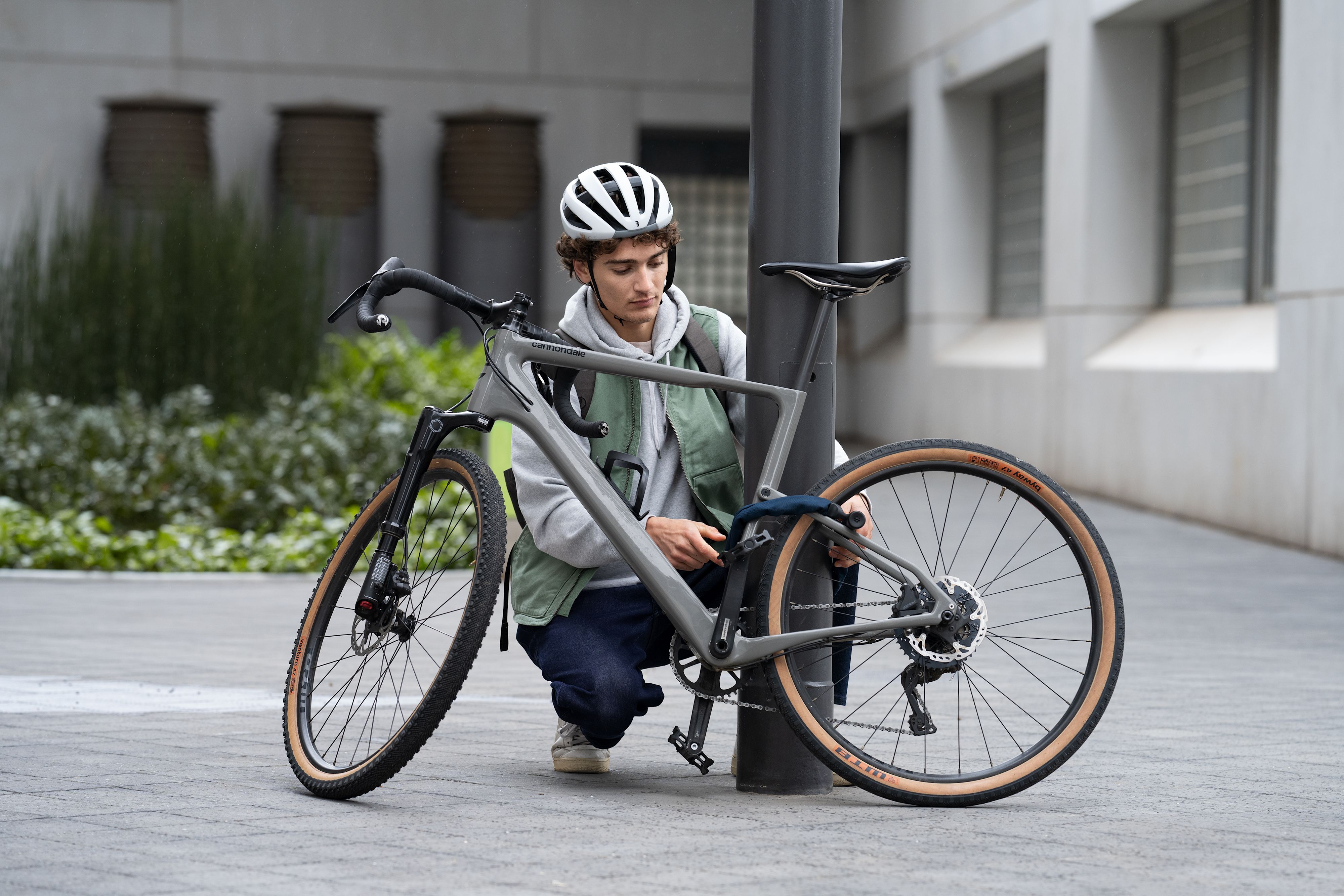 Mann der sein Fahrrad an einer Straßenlaterne abschließt