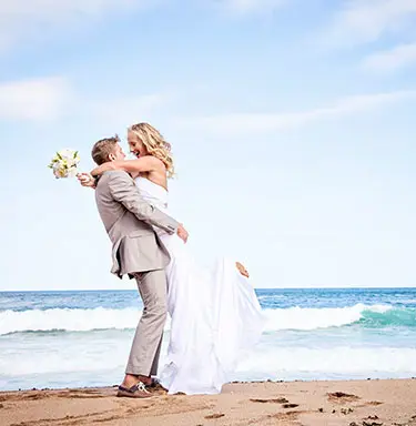 Groom holding bride on the beach