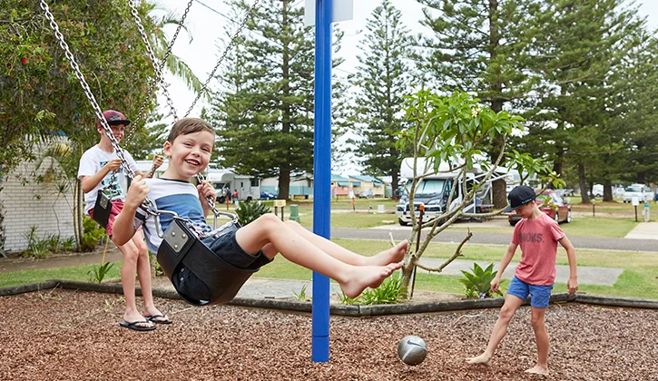 three young boys playing on the swing set at port macquaire