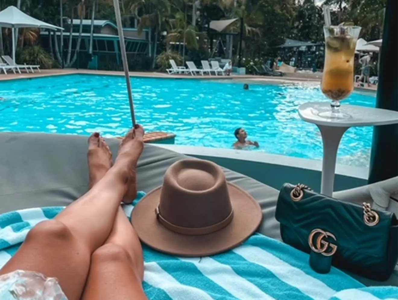 Person laying poolside with cocktail