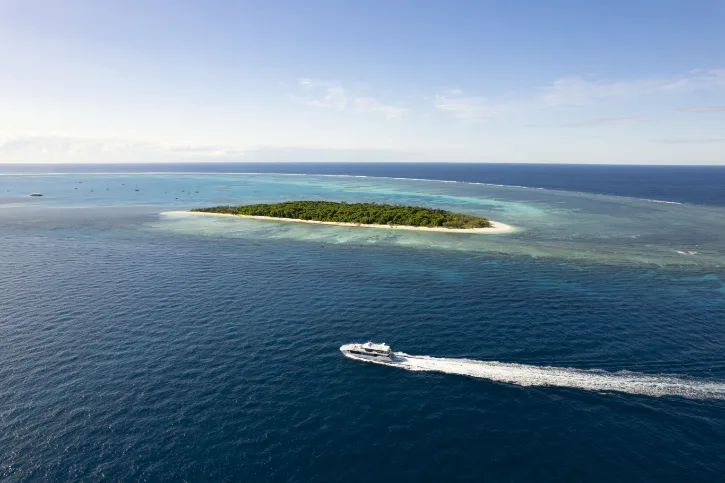 Boat in dark blue waters travelling past Lady Musgrave Island