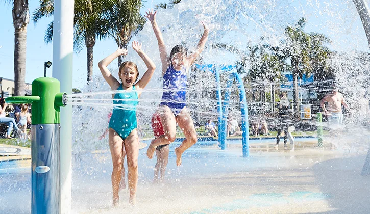 Children splashing in water fountain